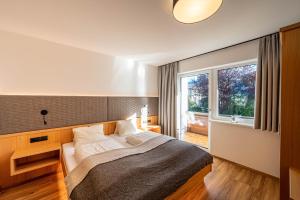 エールヴァルトにあるRustika - Appartements & Spaのベッドルーム1室(ベッド1台、大きな窓付)