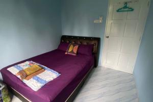 a bed with a purple comforter in a room at Amy Homestay-Suasana kampung yang nyaman in Pasir Mas