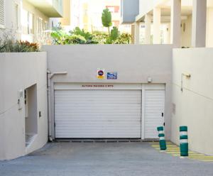 una porta bianca del garage con un cartello sopra di Blue waves - free parking a El Médano