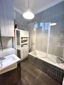 uma casa de banho com um chuveiro, um lavatório e uma banheira em BASSANO em Paris
