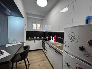 AmIon Apartment in Center of Tirana في تيرانا: مطبخ بخزائن بيضاء ومغسلة وثلاجة