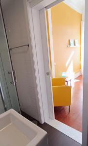 a bathroom with a sink and a yellow chair at Aveiro Rossio Hostel in Aveiro