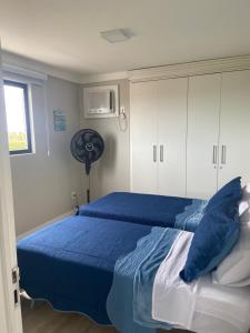 um quarto com 2 camas azuis e uma ventoinha em Ap Cozy Calhau prox PRAIA em São Luís