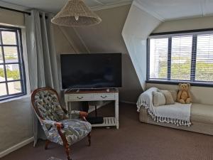 a living room with a tv and a chair and a chair at Vermont Lofts in Hermanus