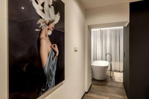 a painting of a woman with birds on the wall of a bathroom at Sellmann´s Boutique Hotel in Dortmund