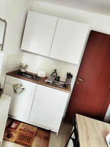 cocina con armarios blancos y puerta roja en Mini Cocco&Fragola, en Reggio Emilia