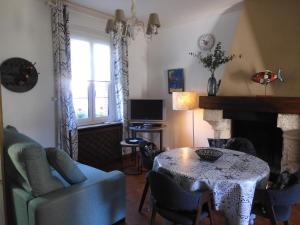 ein Wohnzimmer mit einem Tisch, einem Sofa und einem TV in der Unterkunft LA GOELETTE et son jardin clos sans parking privé in Étretat