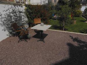 einen Tisch und einen Stuhl auf einer Kiesterrasse in der Unterkunft LA GOELETTE et son jardin clos sans parking privé in Étretat