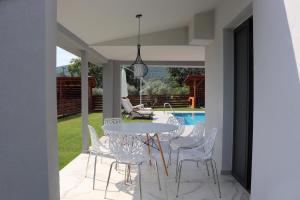 un patio con mesa y sillas junto a una piscina en OLYMPUS Paradise 3, en Skotina