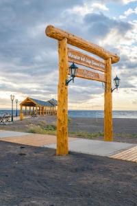 a wooden sign on the beach with the ocean in the background at Casa costanera Lago Buenos Aires, Los Antiguos in Los Antiguos