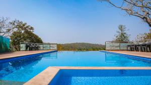 a large swimming pool with blue water and chairs at santanas wooden cottages in Bogmalo