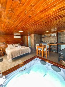 a bedroom with a bed and a hot tub at Cabanas Invernada de Cima in São Joaquim