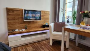 a living room with a desk with a television on a wall at Das Ferienapartment Alexandrine direkt am Pfaffenteich mit eigenem Parkplatz in Schwerin