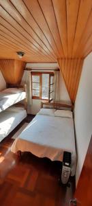 2 łóżka w pokoju z drewnianym sufitem w obiekcie Apartamento em Campos do Jordão próximo ao Capivari w mieście Campos do Jordão