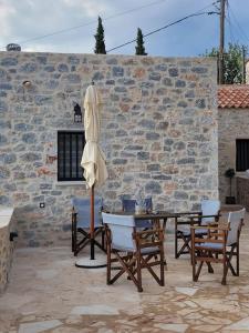 un patio con mesa, sillas y sombrilla en Filia's House (The House of Friendship), en Areopoli