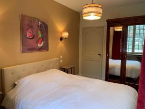 sypialnia z białym łóżkiem i lustrem w obiekcie Charmant appartement jardin/parking privé 4 personnes w mieście Bourboule