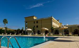 una persona in piedi accanto a una piscina di fronte a un edificio di Parco dei Principi Hotel a Roccella Ionica