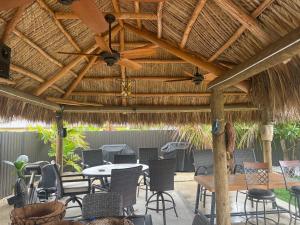 un patio avec des tables et des chaises sous un toit de chaume dans l'établissement Paradise Oasis1, à Miami