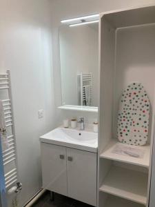 een witte badkamer met een wastafel en een spiegel bij Disney cocooning à 5 minutes du Parc in Coupvray