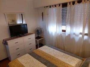 1 dormitorio con 1 cama, TV y ventana en Apartamento Unico Miramar en Miramar