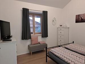 a bedroom with a bed and a chair and a television at Ferienwohnung zum Peterbauer in Sachsenkam