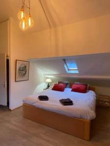 a bedroom with a large bed with red pillows at The Charm in Bouillon