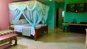 a bedroom with a canopy bed and a desk at Armaan Guest House in Diani Beach