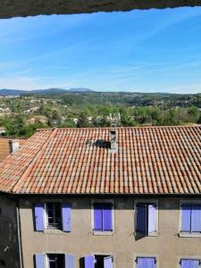 a building with a tile roof with purple windows at Joyeuse, superbe appartement d'environs 30m2. in Joyeuse