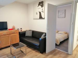 a living room with a black leather couch and a bed at Joyeuse, appartement de 27m2 in Joyeuse