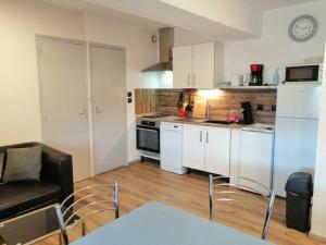 a kitchen with a couch and a table in a room at Joyeuse, appartement de 27m2 in Joyeuse