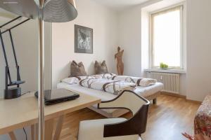 ein Wohnzimmer mit einem Sofa und einem Schreibtisch mit einem Laptop in der Unterkunft Victoria Apartment in Bozen