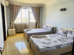 2 camas en una habitación con ventana en Masaki Anne H & Apartment, en Dar es Salaam
