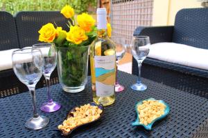 - une table avec une bouteille de vin, des verres et des fleurs dans l'établissement Kyma Flat, à Nebida