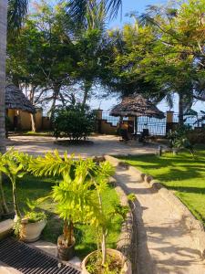 a garden with palm trees and a path at Masaki Anne H & Apartment in Dar es Salaam