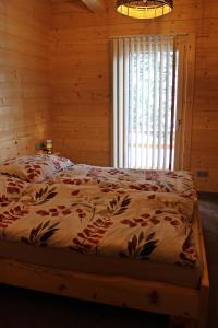 een bed in een houten kamer met een raam bij Sonnenblickhütte in Klippitztorl