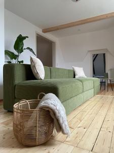 a living room with a green couch and a basket at Kulturgenuss am Goethewanderweg in Weimar