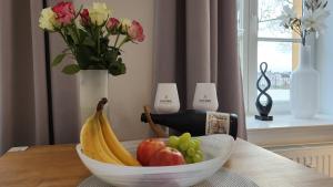 a bowl of fruit on a table with a vase of flowers at Das Ferienapartment Alexandrine direkt am Pfaffenteich mit eigenem Parkplatz in Schwerin +20 photos