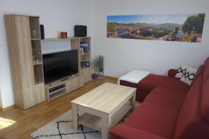 sala de estar con sofá rojo y TV en Pod Chlumem - útulný byt v blízkosti centra, en Děčín