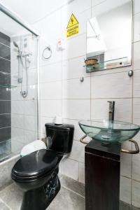 a bathroom with a black toilet and a sink at Huanchaco Paradise Hotel in Huanchaco