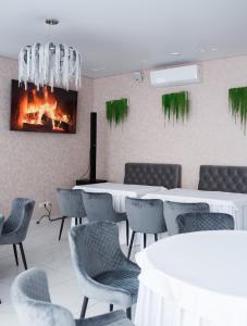 restauracja ze stołami i krzesłami oraz kominkiem w obiekcie Hotel VinoGrad w mieście Haysyn