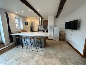 a kitchen with a large island with bar stools at La Maison du Moulin à Vent in La ForestiÃ¨re