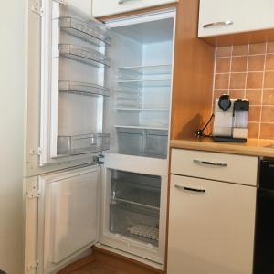 une cuisine avec un réfrigérateur vide et une porte ouverte dans l'établissement Landhaus Klausner, à Saalbach-Hinterglemm