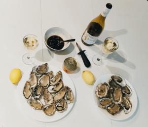 a table with two plates of oysters and a bottle of wine at Chalet prestige au coeur du Bassin d'Arcachon in La Teste-de-Buch