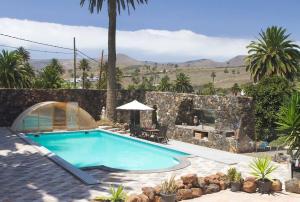 uma piscina num quintal com uma parede de pedra em Casita Palmera, Country Home, Haria, Lanzarote em Haría