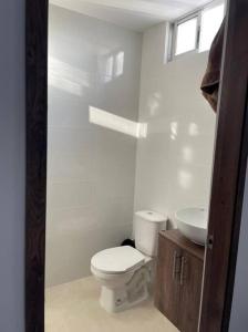 a white bathroom with a toilet and a sink at Apartamento pitalito in Pitalito