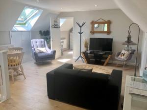 ein Wohnzimmer mit einem Sofa, Stühlen und einem TV in der Unterkunft Harrow Hayloft Rural 80m2 Village Hideaway Retreat in Himbleton