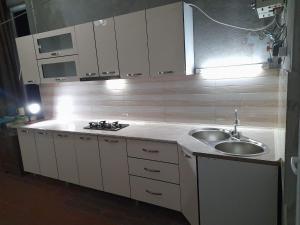 una cucina con armadi bianchi e lavandino di Levani's GuestHouse a Zugdidi