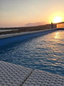 una piscina con il tramonto sullo sfondo di Sofia Villas Pounta Beach ad Afiartis