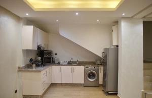 a kitchen with white cabinets and a washer and dryer at Magnifique Duplex à Marrakech in Marrakech