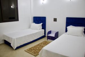 - 2 lits dans un dortoir bleu et blanc dans l'établissement Magnifique Duplex à Marrakech, à Marrakech